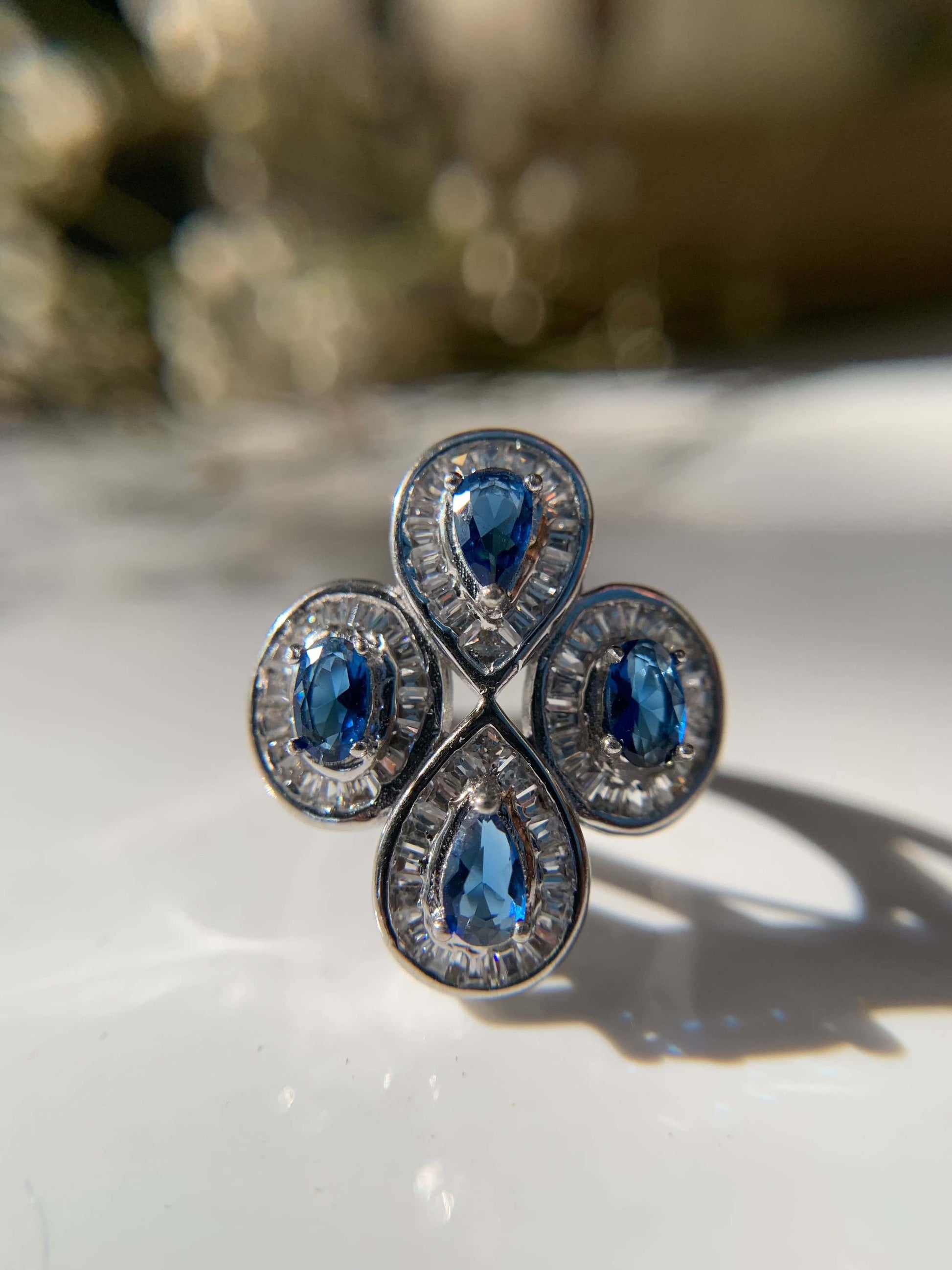 Blue cocktail ring with teardrop gemstones and ornate silver detailing.
