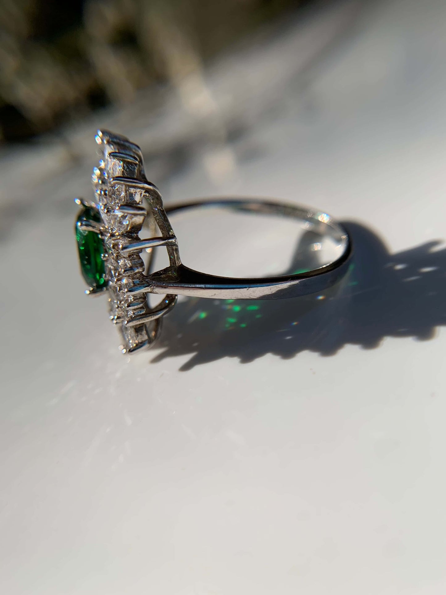 Green cocktail ring with silver band and gemstone accents.