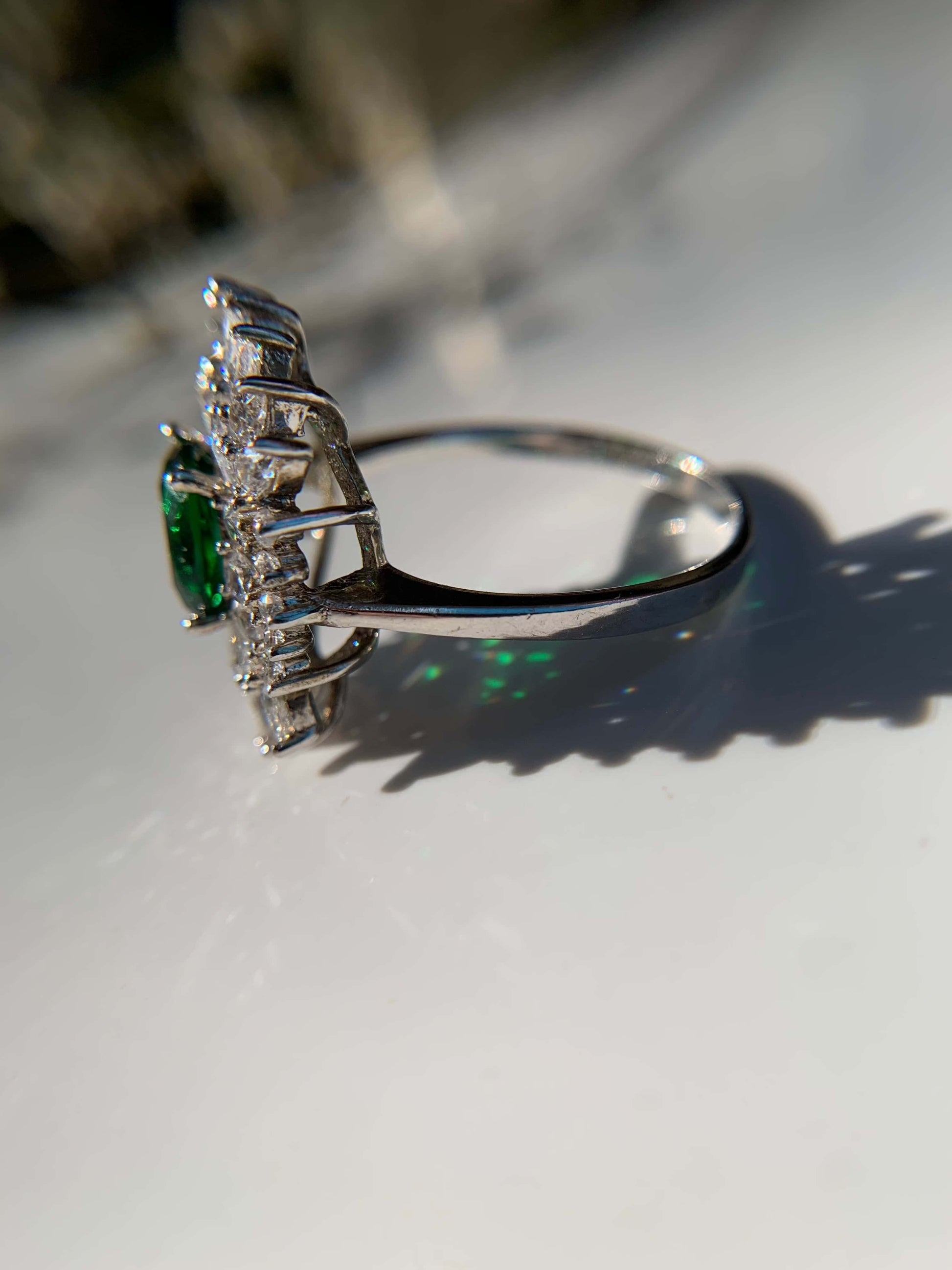 Green cocktail ring with silver band and gemstone accents.
