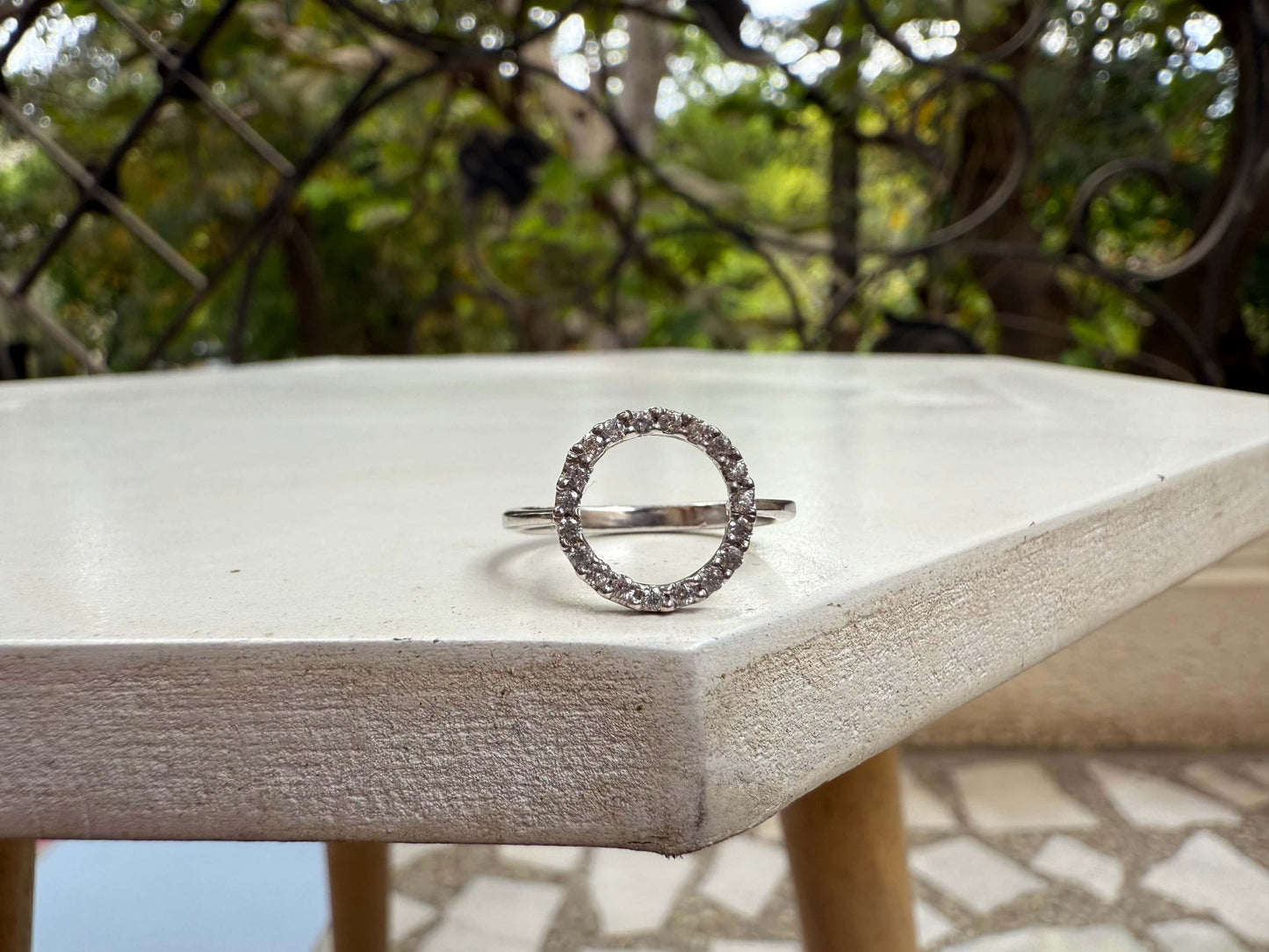 Halo Ring with sparkling gems on a round outdoor table.