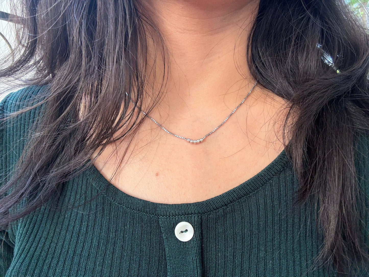Five Dot Curved Pendant necklace worn on woman's neck.