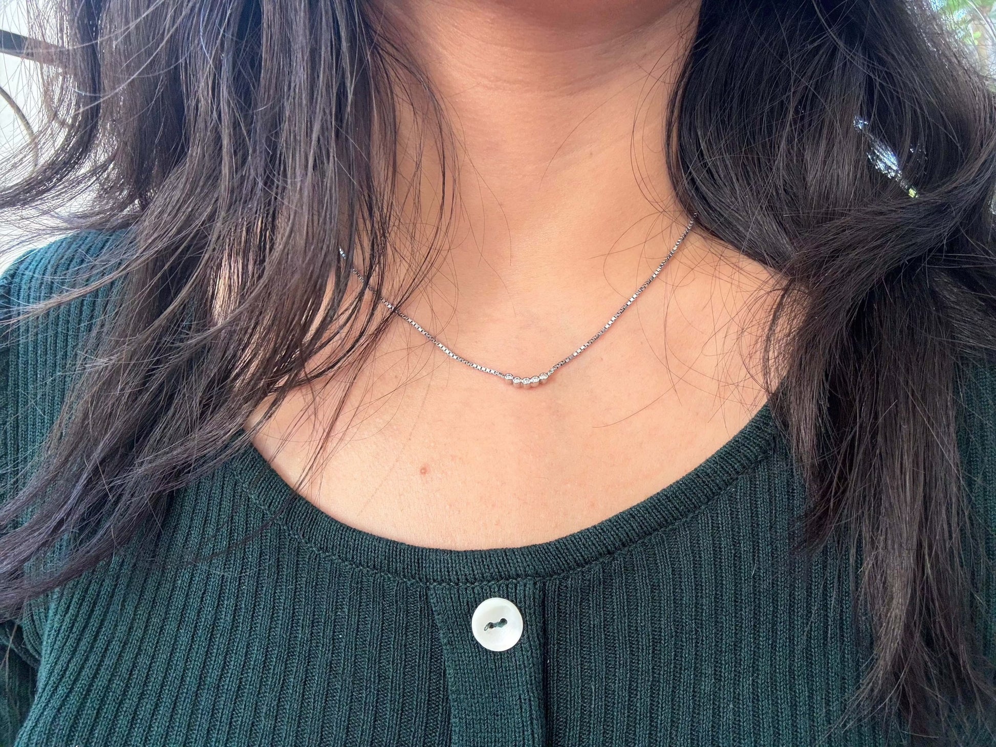 Five Dot Curved Pendant necklace worn on woman's neck.