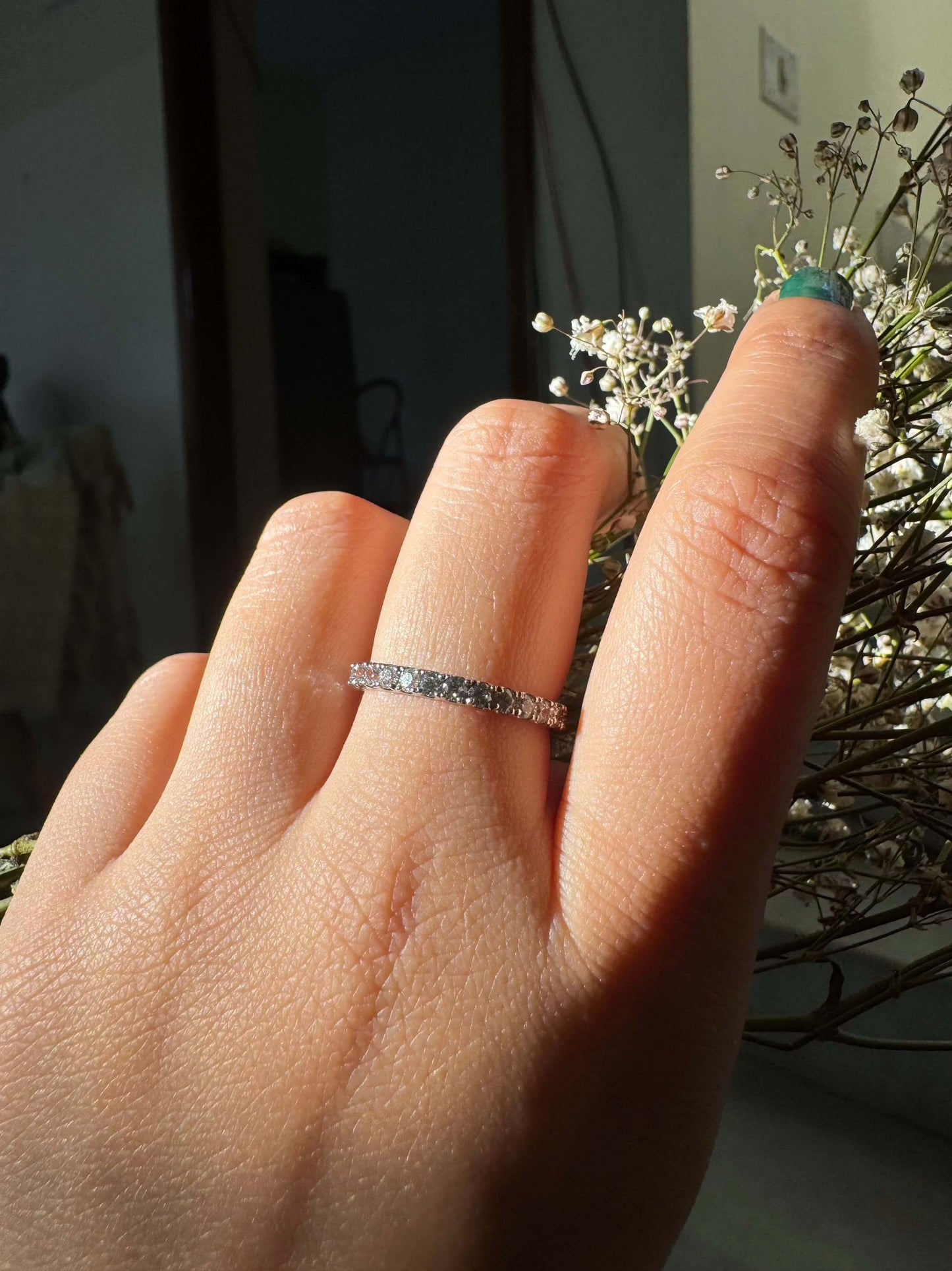 Classic Shine Line Ring on finger with delicate floral background.