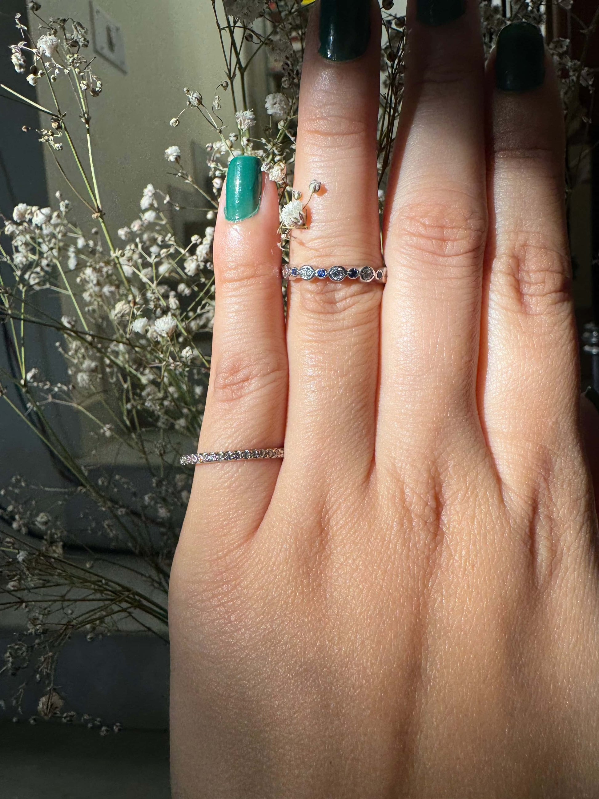 Classic Shine Line Ring on finger with delicate floral backdrop.