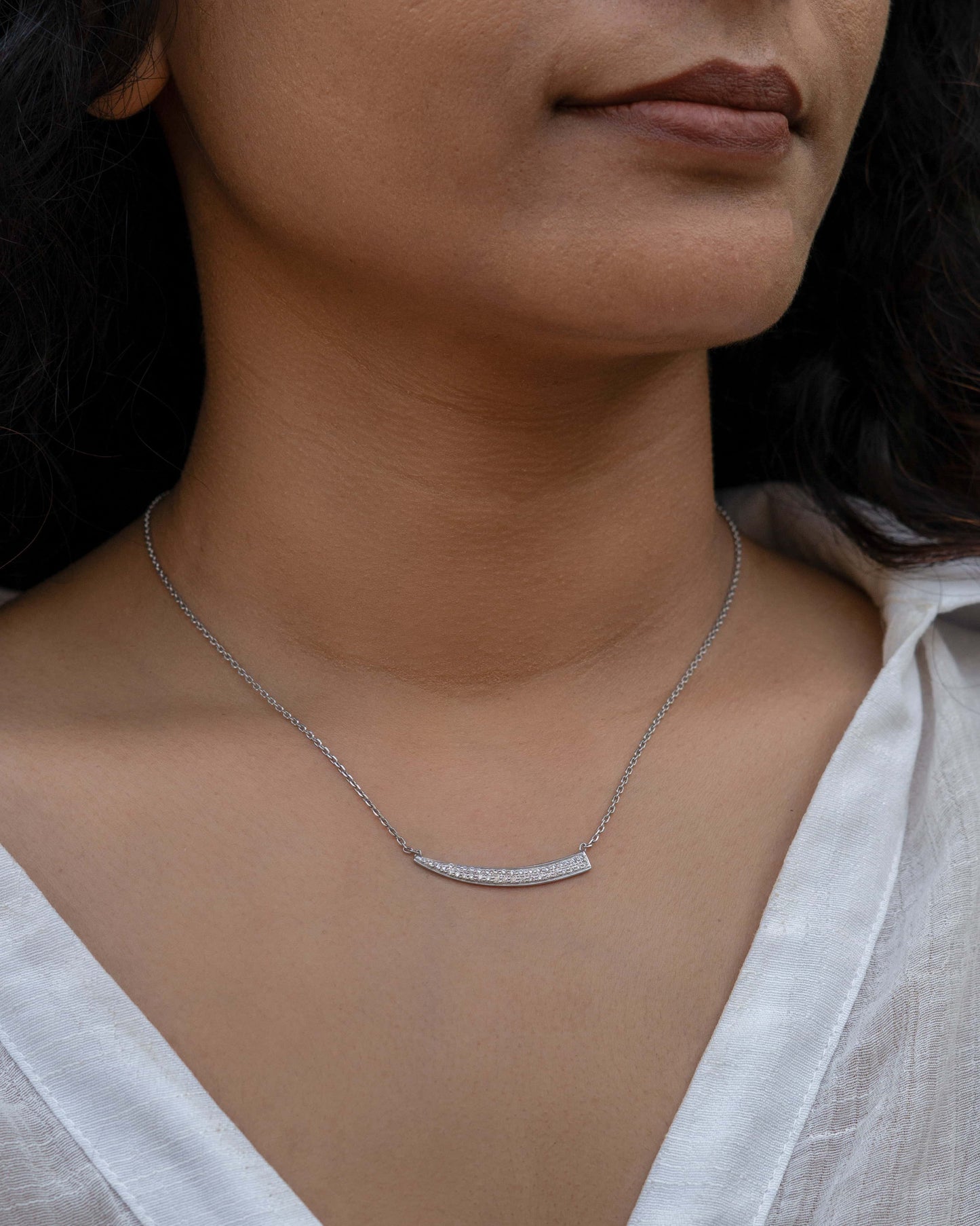 Elegant sward pendant necklace worn by a person in a white shirt.