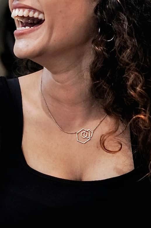 Rose pendant necklace worn by a smiling woman.