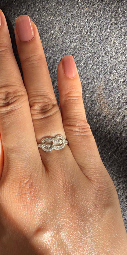 Hand wearing an elegant infinity ring with a delicate design.
