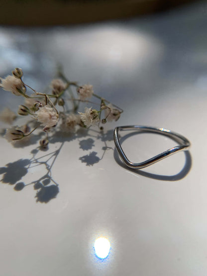 Sleek Mount Ring beside delicate flowers on a glossy surface.