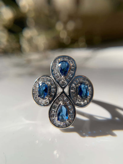 Blue cocktail ring with teardrop gemstones and ornate silver detailing.