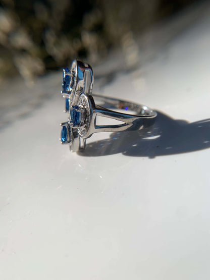 Blue cocktail ring with silver band and blue gemstones.