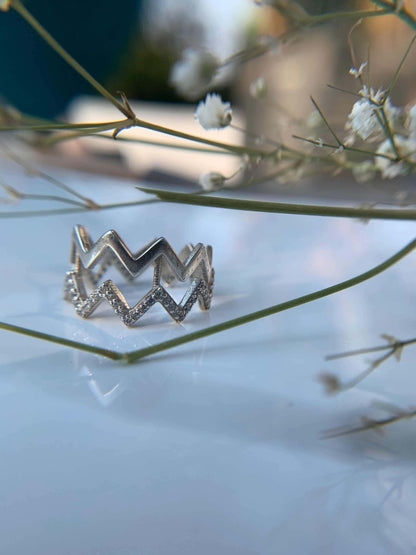 Z Layer Ring with zigzag design on a reflective surface.