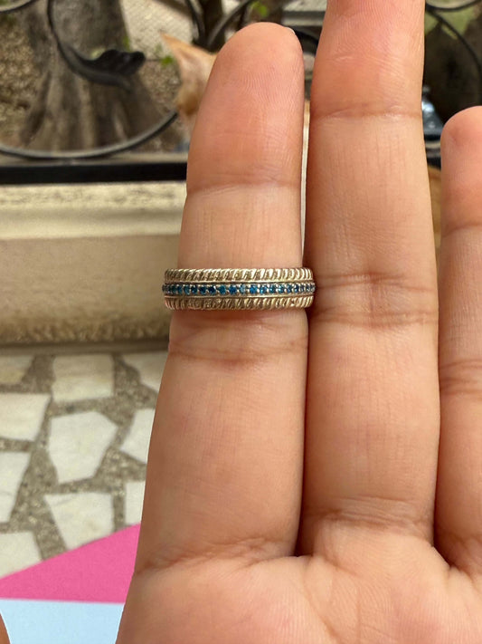 Gold ring with blue line on finger.