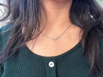Five Dot Curved Pendant necklace worn on woman's neck.