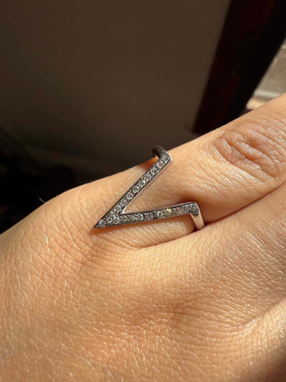 Silver V Ring with sparkling stones worn on a finger.