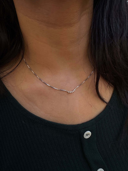 Five Dot Curved Pendant necklace displayed on a person wearing a dark top.
