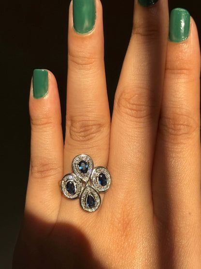 Blue cocktail ring with sapphire stones on a hand.