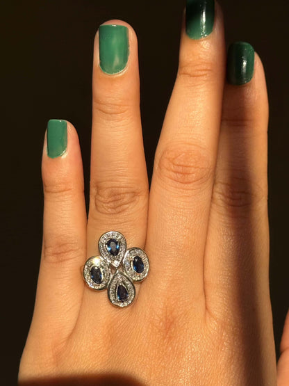Blue cocktail ring with multiple blue gemstones on a hand.