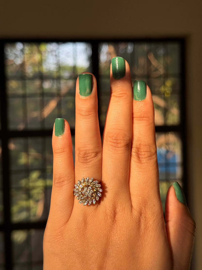 Yellow cocktail ring on hand with green nail polish.