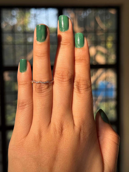 Hand wearing Three Peak Ring with green nail polish in natural light.