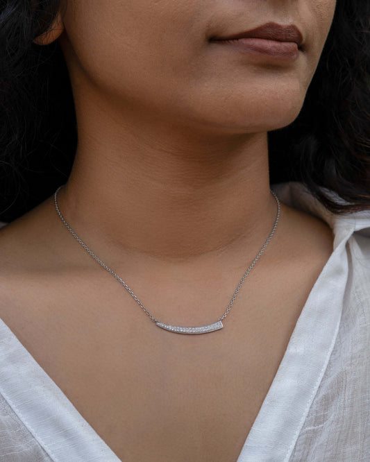 Elegant sward pendant necklace worn by a person in a white shirt.
